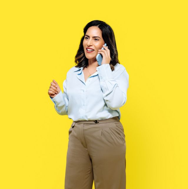 Ines in front of yellow background talking on the phone